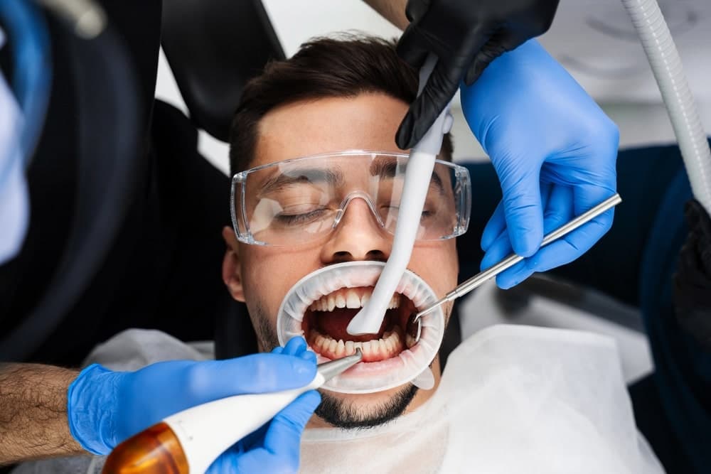 Dental hygienist performing AIRFLOW treatment on a patient