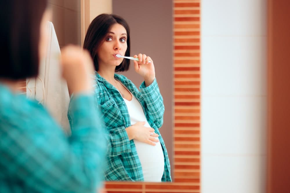 Pregnant woman brushing teeth maintaining oral hygiene