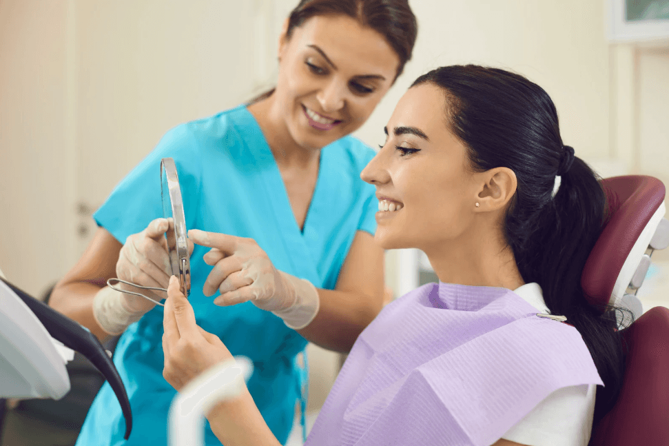 Dentist and a satisfied dental patient assessing artificial teeth before and after All-on-4 dental implants.