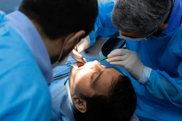 Two dental surgeons operate on a patient.