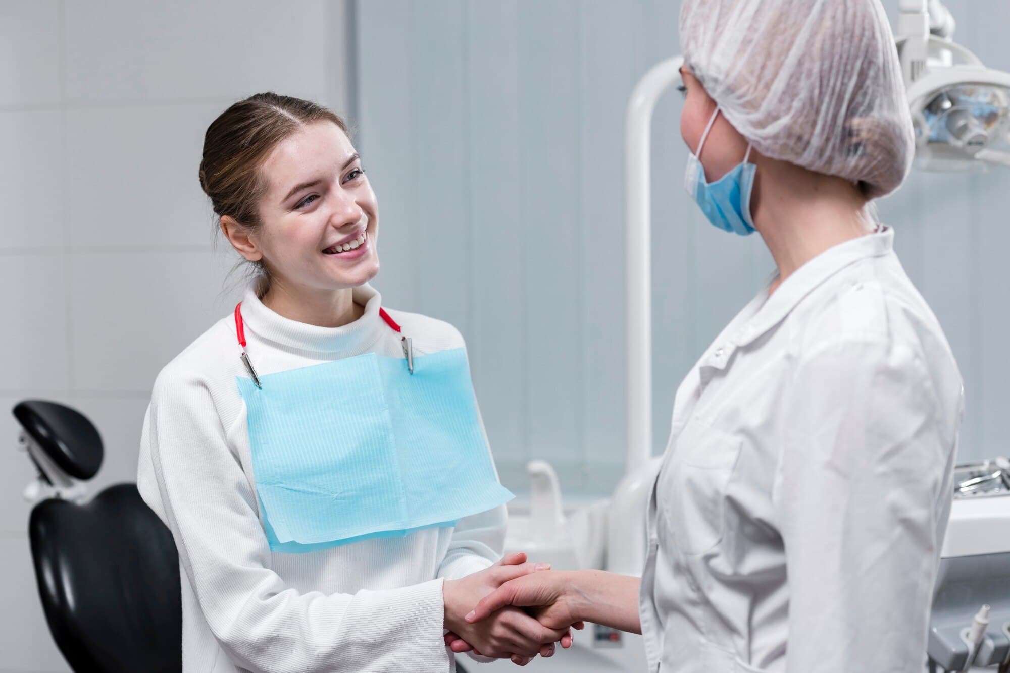 A happy patient shakes hands with a dentist.