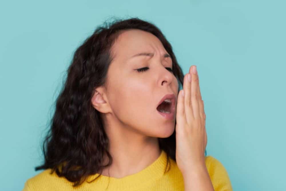 Person covering their mouth with their hand, concerned about bad breath