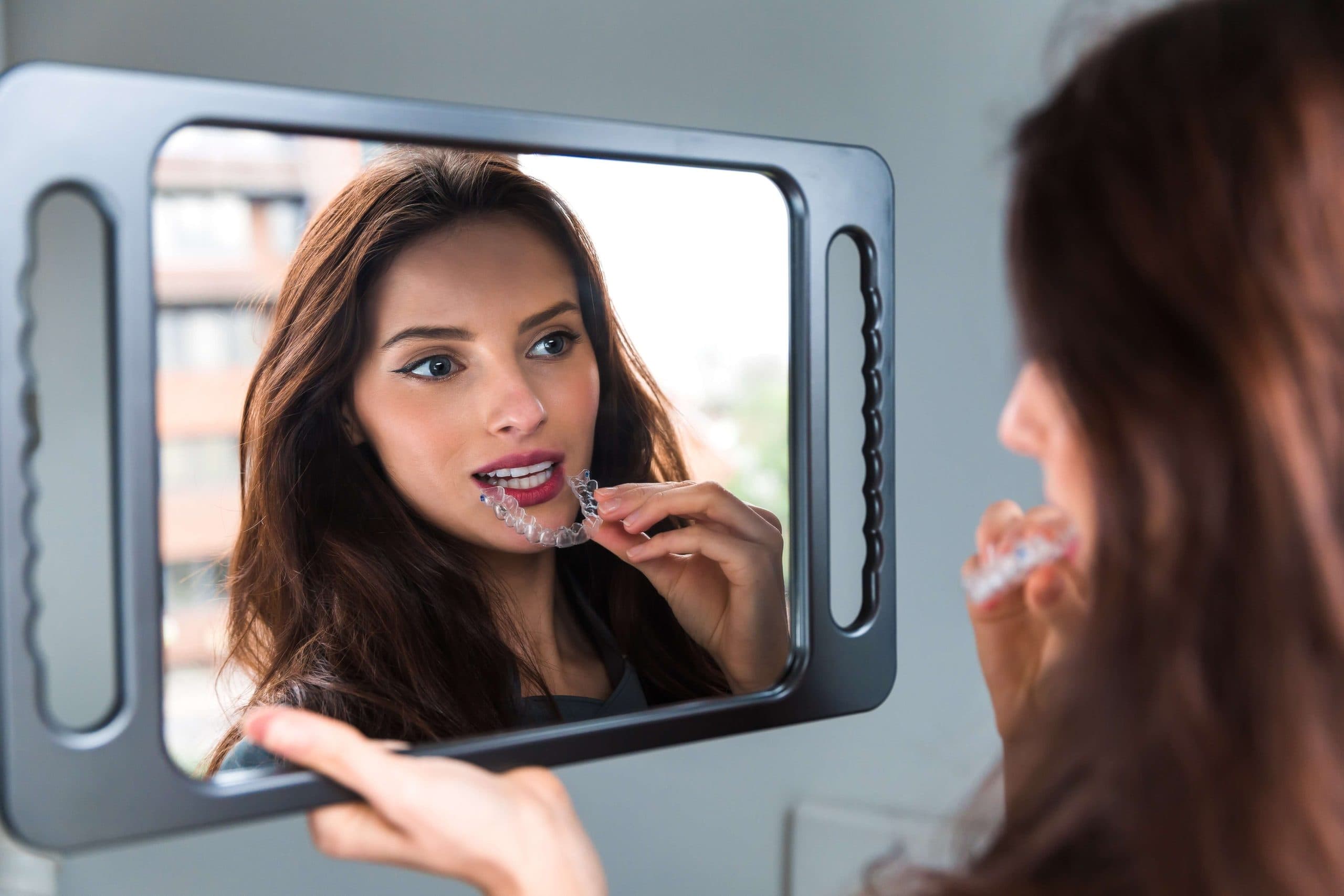 Person cleaning Invisalign aligners with a soft toothbrush