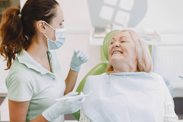 An elderly, smiling woman undergoes a dental procedure.