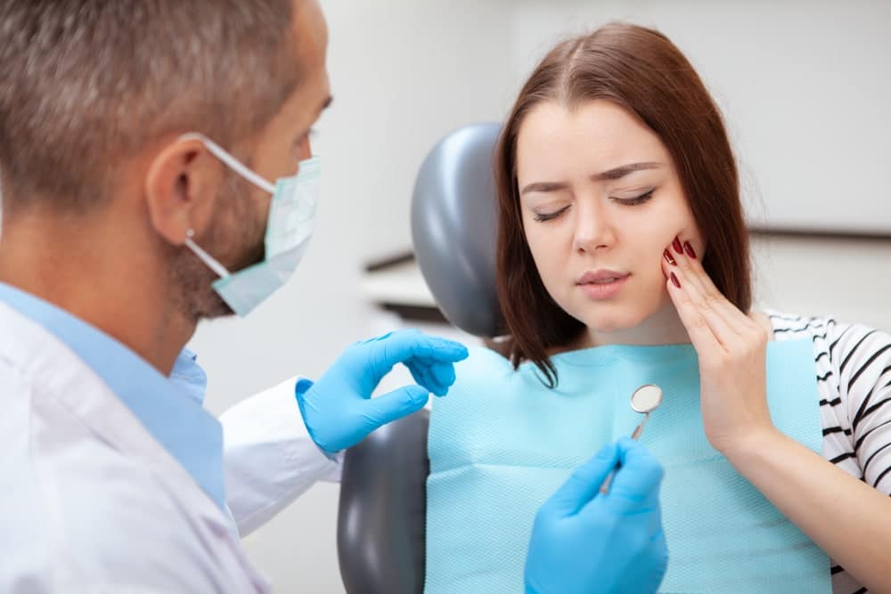 Person holding their cheek in pain from a toothache